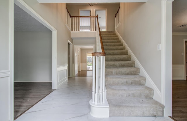 11022 Riverview Dr, Houston, TX 77042 - stairs with a decorative wall, crown molding, wood finished floors, and wainscoting