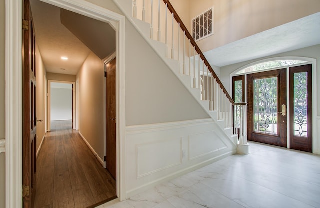 11022 Riverview Dr, Houston, TX 77042 - entrance foyer with visible vents, a decorative wall, wainscoting, and stairs