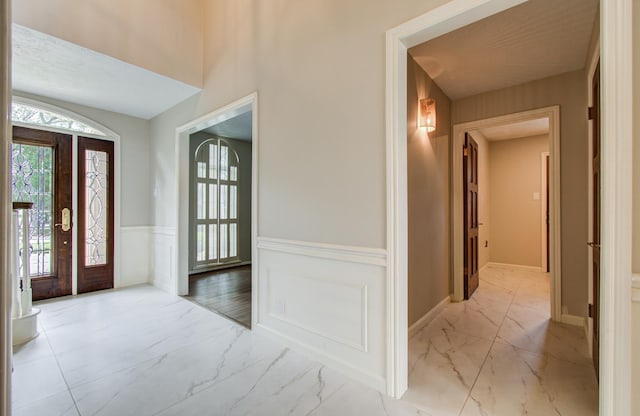 11022 Riverview Dr, Houston, TX 77042 - foyer entrance featuring marble finish floor, a healthy amount of sunlight, and a wainscoted wall
