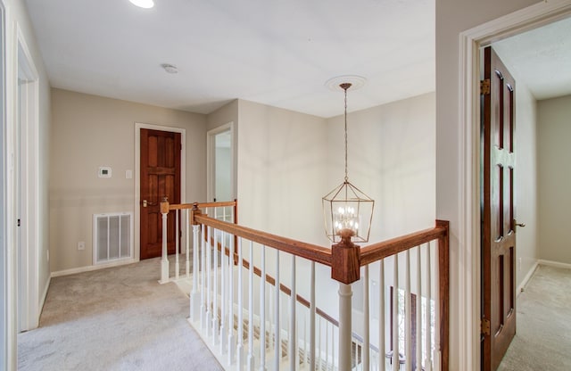 11022 Riverview Dr, Houston, TX 77042 - hall with a notable chandelier, baseboards, visible vents, light carpet, and an upstairs landing