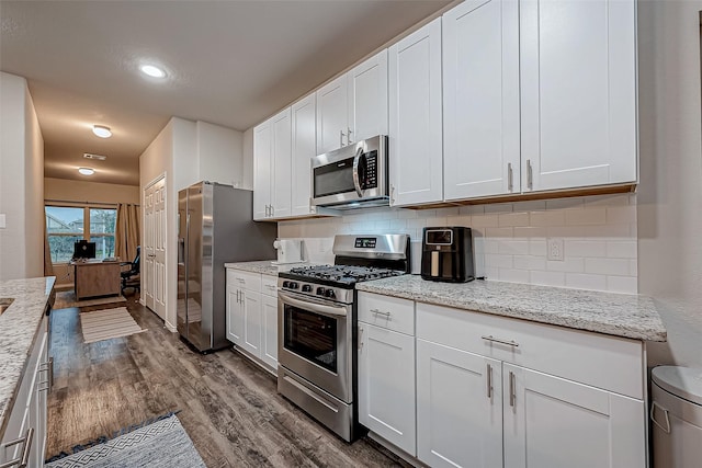 kitchen featuring white cabinetry, stainless steel appliances, backsplash, and dark wood-type flooring