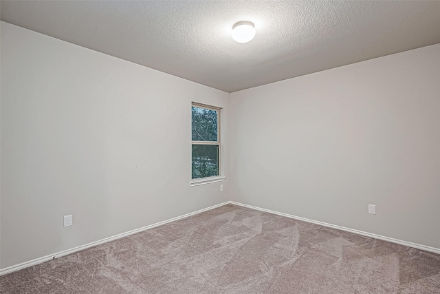 unfurnished room featuring carpet, a textured ceiling, and baseboards
