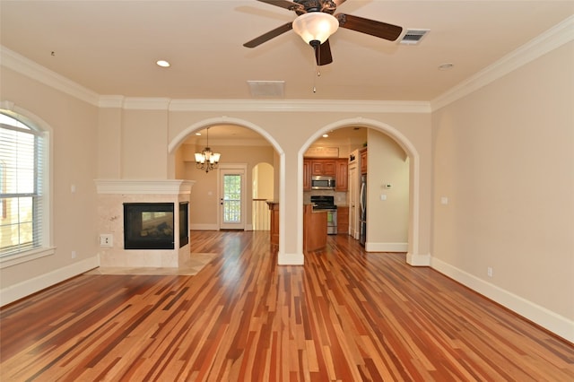 unfurnished living room with visible vents, crown molding, light wood-style flooring, arched walkways, and a tile fireplace