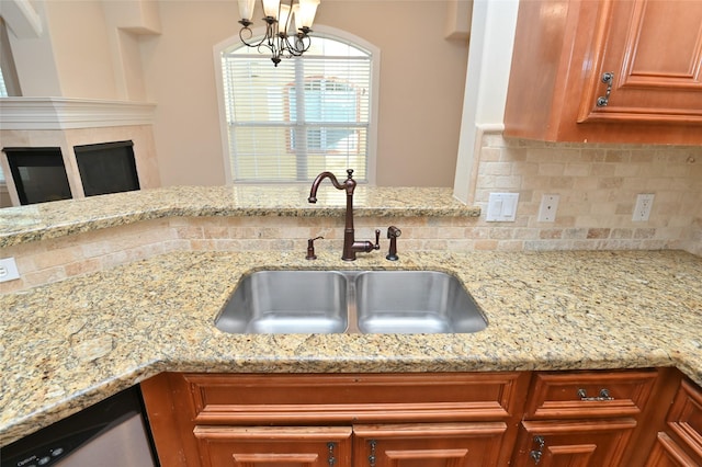 kitchen with brown cabinets, light stone counters, decorative backsplash, and a sink