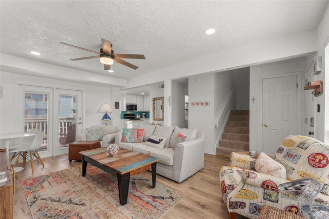 501 Jean Lafitte Cv, Galveston, TX 77554 - living area featuring light wood-style floors, a textured ceiling, a ceiling fan, and stairs