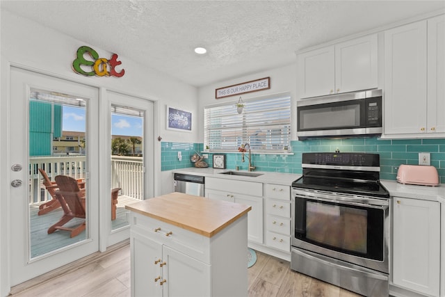 501 Jean Lafitte Cv, Galveston, TX 77554 - kitchen with light wood finished floors, stainless steel appliances, white cabinets, and a sink