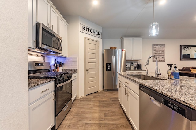 9705 Wall St, Texas City, TX 77591 - kitchen with white cabinets, appliances with stainless steel finishes, light stone counters, and a sink