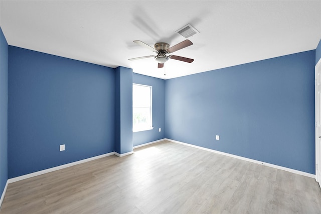 spare room featuring baseboards, ceiling fan, visible vents, and wood finished floors