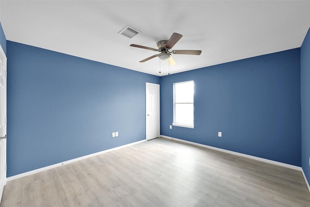 unfurnished room featuring baseboards, visible vents, wood finished floors, and a ceiling fan
