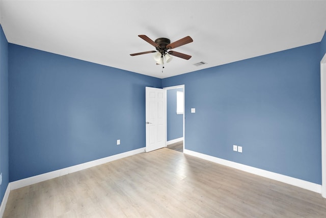 empty room featuring wood finished floors, visible vents, baseboards, and a ceiling fan