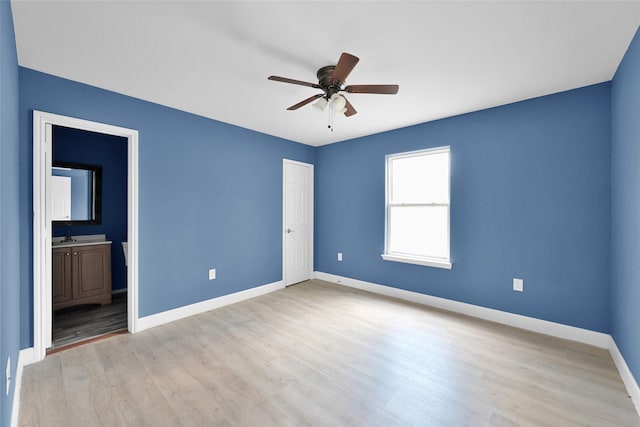 unfurnished bedroom with a closet, ensuite bath, ceiling fan, baseboards, and light wood-style floors