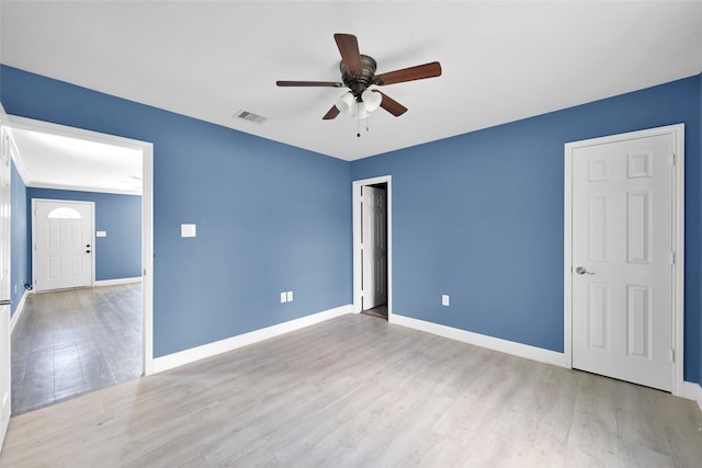 unfurnished bedroom with baseboards, ceiling fan, visible vents, and wood finished floors