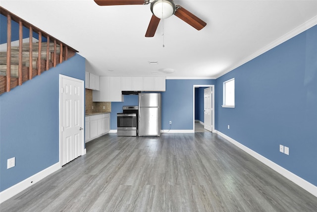 unfurnished living room featuring ceiling fan, crown molding, baseboards, and wood finished floors