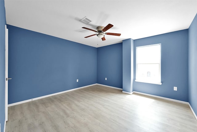 spare room with ceiling fan, baseboards, visible vents, and wood finished floors