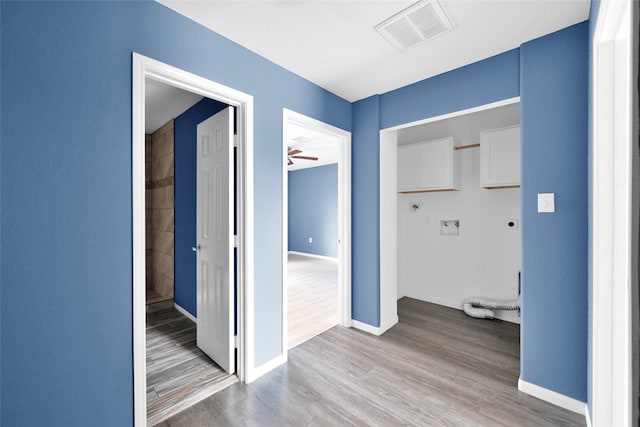 hallway featuring baseboards, visible vents, and wood finished floors