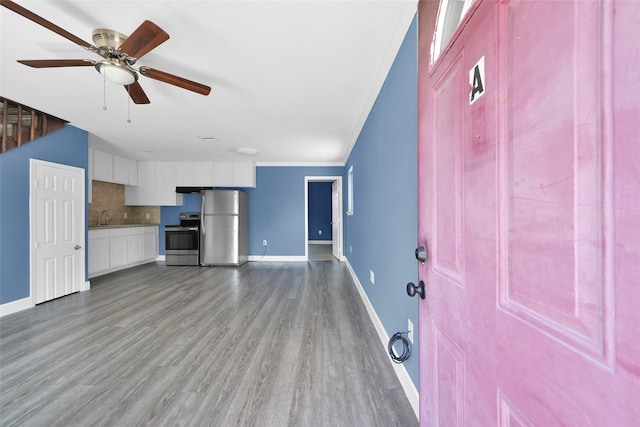 unfurnished living room featuring a sink, ceiling fan, baseboards, and wood finished floors