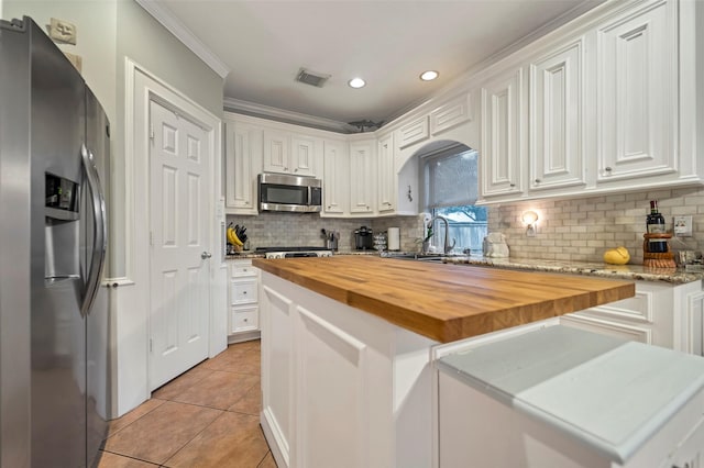 9203 Baber Run Cir, Houston, TX 77095 - kitchen with appliances with stainless steel finishes, butcher block countertops, light tile patterned floors, white cabinetry, and ornamental molding