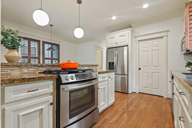 kitchen featuring appliances with stainless steel finishes, light wood-type flooring, pendant lighting, white cabinets, and crown molding