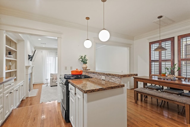 kitchen with stainless steel electric range, light wood-type flooring, white cabinets, dark stone countertops, and crown molding