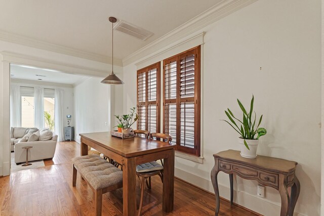 dining space featuring ornamental molding, light wood-style floors, and baseboards