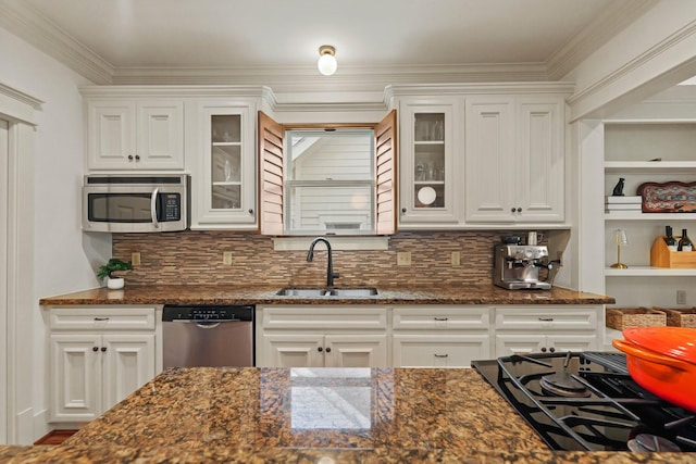 kitchen with appliances with stainless steel finishes, a sink, white cabinetry, glass insert cabinets, and crown molding