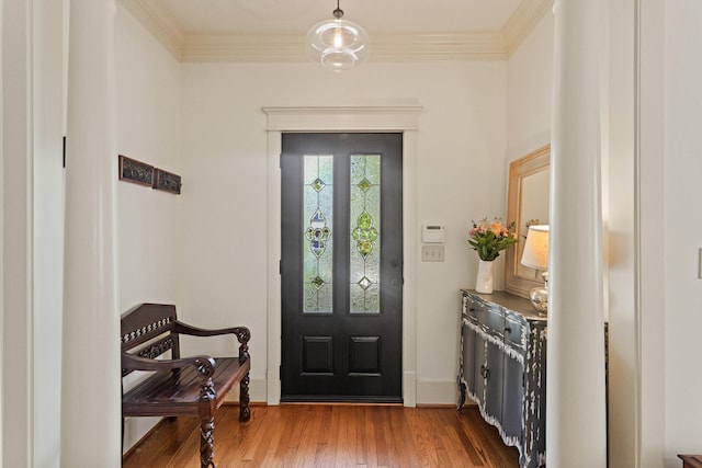 foyer featuring wood finished floors, baseboards, and ornamental molding