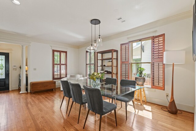 dining room featuring ornamental molding, light wood-style flooring, ornate columns, and baseboards