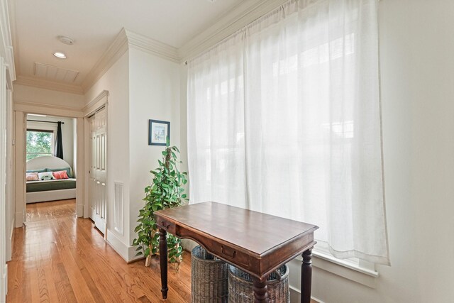 hallway with ornamental molding, light wood-style floors, and baseboards