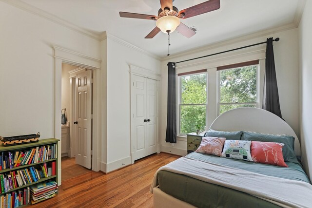 bedroom featuring light wood-style floors, crown molding, a ceiling fan, baseboards, and a closet
