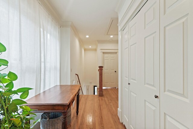 hall with an upstairs landing, attic access, light wood-style flooring, ornamental molding, and recessed lighting