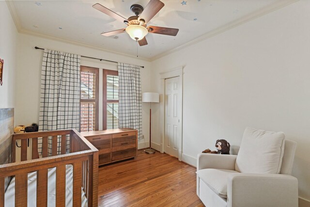 bedroom with light wood-type flooring, crown molding, baseboards, and ceiling fan