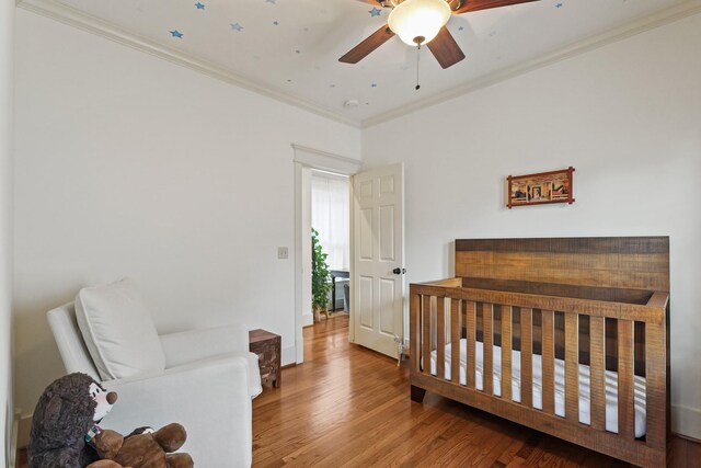 bedroom with wood finished floors and crown molding