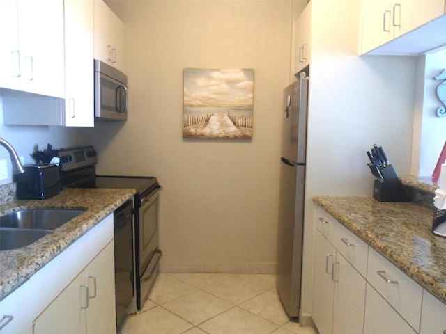 1401 E Beach Dr Unit 809, Galveston, TX 77550 - kitchen with appliances with stainless steel finishes, a sink, white cabinetry, baseboards, and light stone countertops