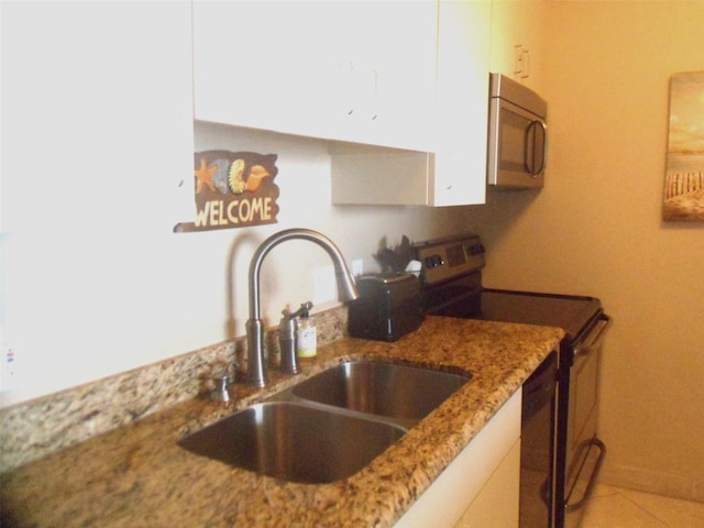 1401 E Beach Dr Unit 809, Galveston, TX 77550 - kitchen featuring appliances with stainless steel finishes, a sink, light stone countertops, and white cabinets