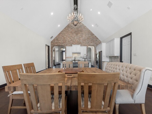 dining space featuring arched walkways, high vaulted ceiling, and a chandelier