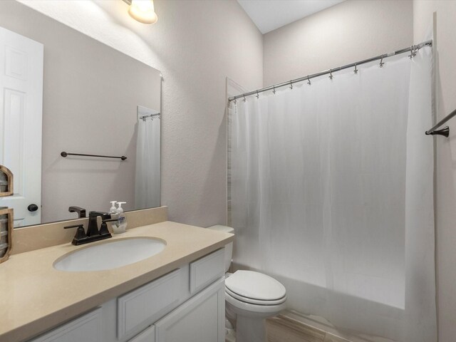 bathroom featuring toilet, vanity, and shower / tub combo with curtain
