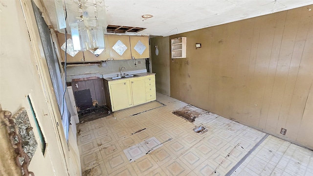 1314 Burbank St, Baytown, TX 77520 - kitchen with light floors, wood walls, cream cabinetry, and a sink