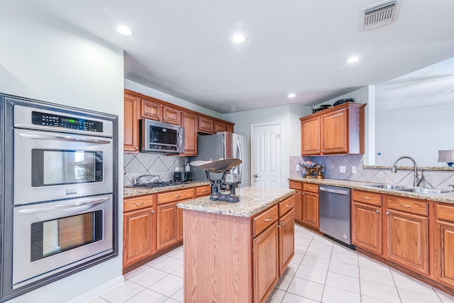 410 Scarlet Sage Dr, League City, TX 77573 - kitchen featuring appliances with stainless steel finishes, tasteful backsplash, light tile patterned floors, a center island, and light stone countertops