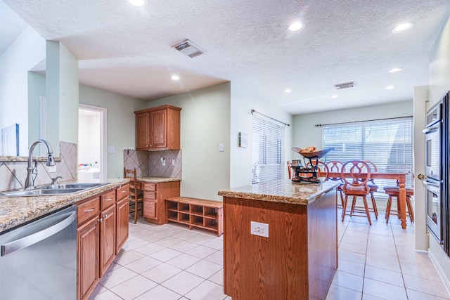 410 Scarlet Sage Dr, League City, TX 77573 - kitchen with appliances with stainless steel finishes, brown cabinetry, decorative backsplash, light tile patterned flooring, and recessed lighting