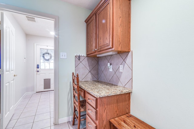 410 Scarlet Sage Dr, League City, TX 77573 - kitchen with light tile patterned floors, backsplash, brown cabinets, and light stone counters