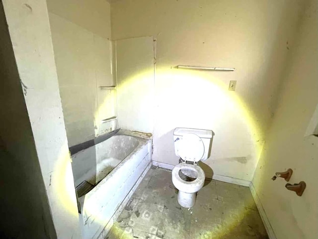 full bathroom with toilet, baseboards, and a bath