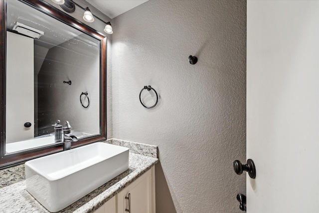 bathroom with a textured wall and vanity