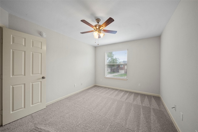 carpeted empty room featuring ceiling fan, baseboards, and a smoke detector