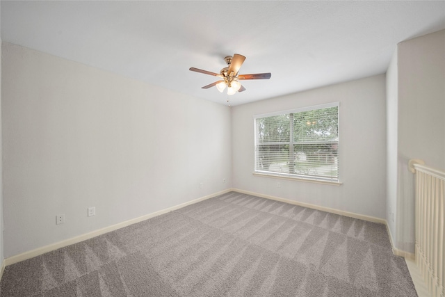 carpeted spare room with a ceiling fan and baseboards