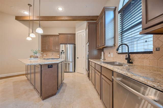 kitchen with hanging light fixtures, a sink, light stone countertops, backsplash, and appliances with stainless steel finishes