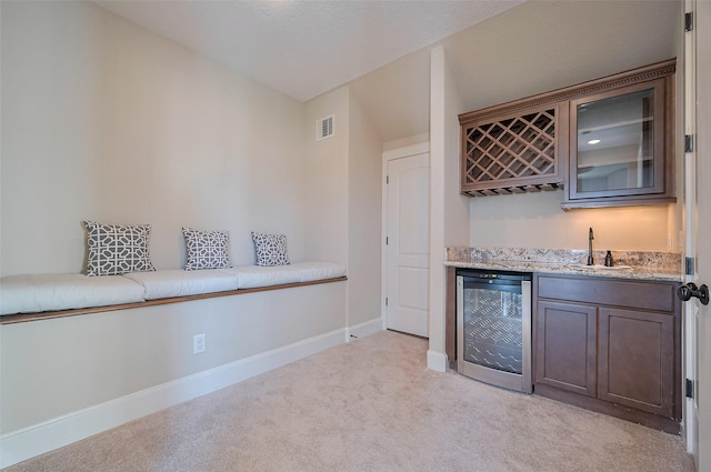 bar featuring indoor wet bar, wine cooler, visible vents, light carpet, and baseboards