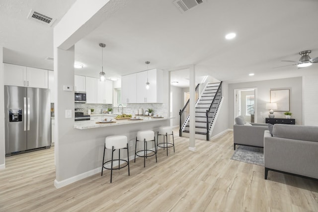 1819 Redwood Ct, Sugar Land, TX 77498 - kitchen with light wood finished floors, a kitchen bar, visible vents, and appliances with stainless steel finishes