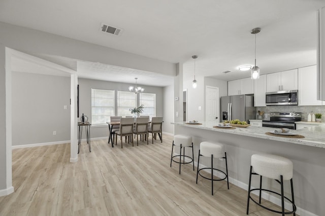 1819 Redwood Ct, Sugar Land, TX 77498 - kitchen featuring stainless steel appliances, tasteful backsplash, a kitchen breakfast bar, and light wood-type flooring
