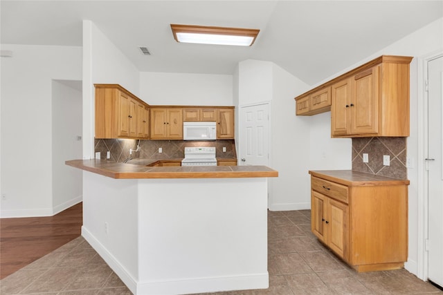 kitchen with white appliances, decorative backsplash, a peninsula, baseboards, and light tile patterned floors