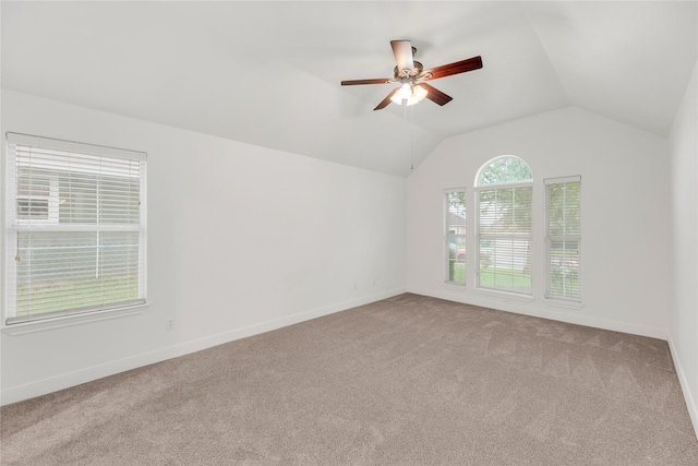 spare room with carpet, a ceiling fan, vaulted ceiling, and baseboards